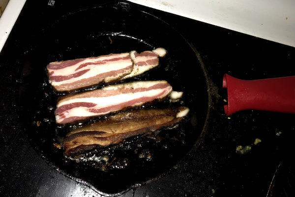 bacon frying in a cast iron pan