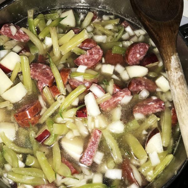 green bean soup in pot with wooden spoon