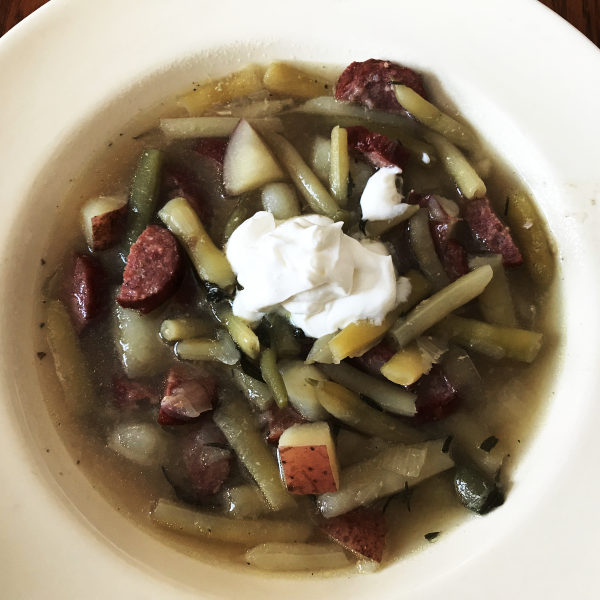 green bean soup in a bowl with a dollop of sour cream