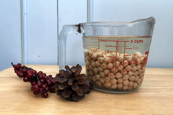 chickpeas soaking in water in a measuring cup