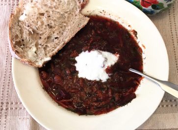 beet soup in bowl with slice of bread