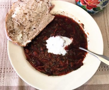 beet soup in bowl with slice of bread
