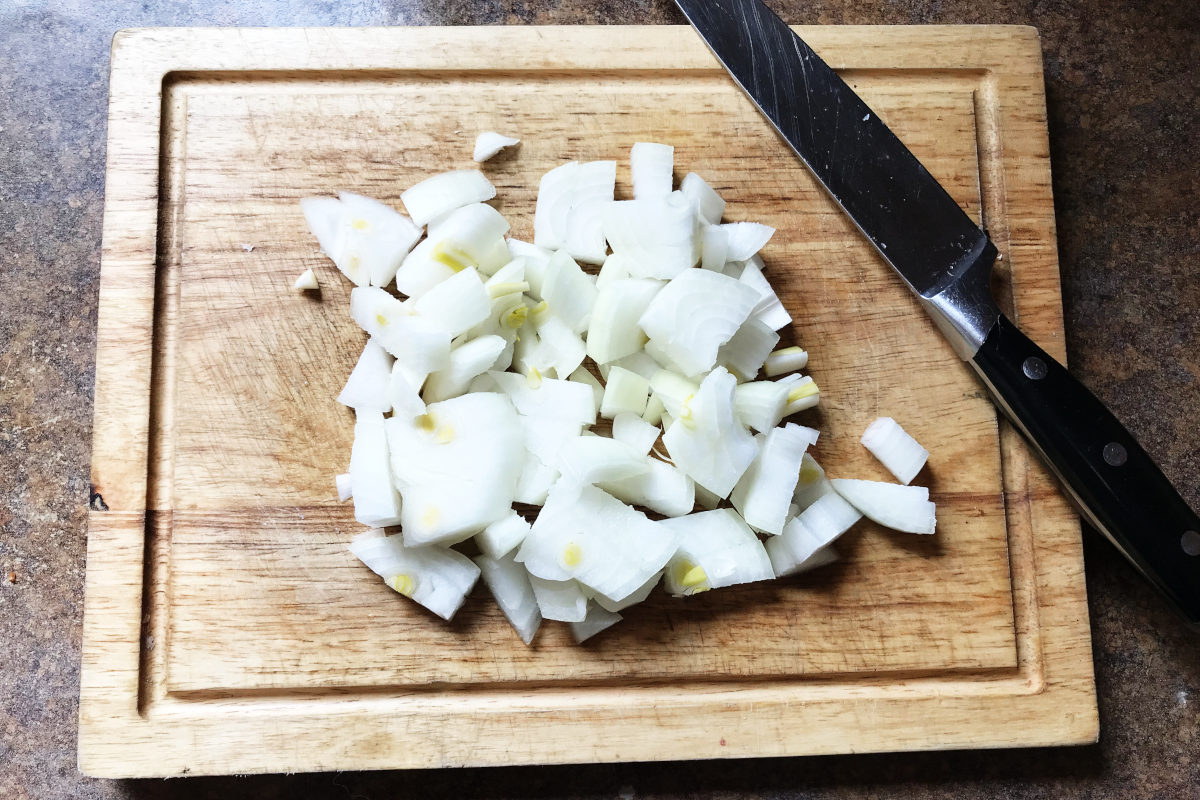 chopped onions on wooden cutting board with knife