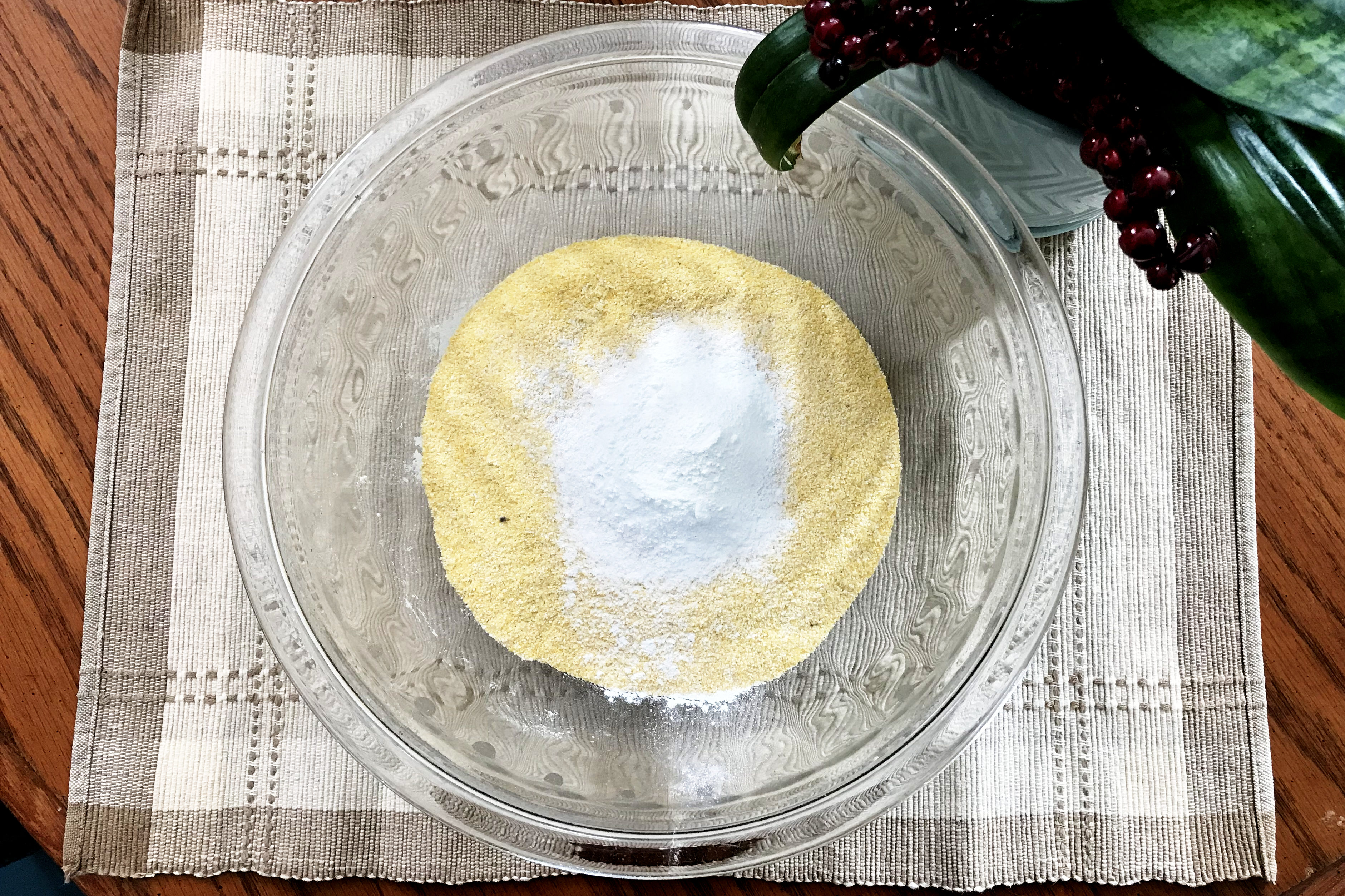 mixing bowl with cornmeal, baking powder, baking soda and salt, on placemat