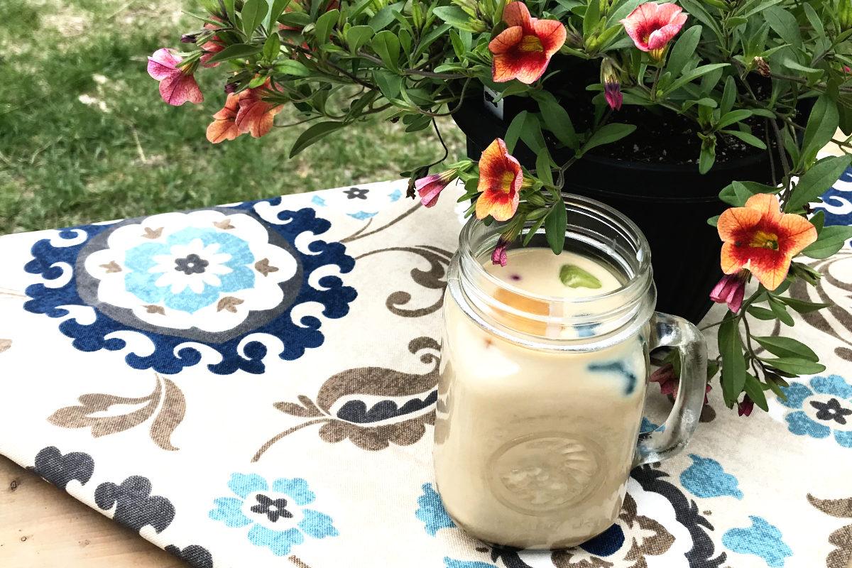 jar of ice coffee on place mat next to potted flowers