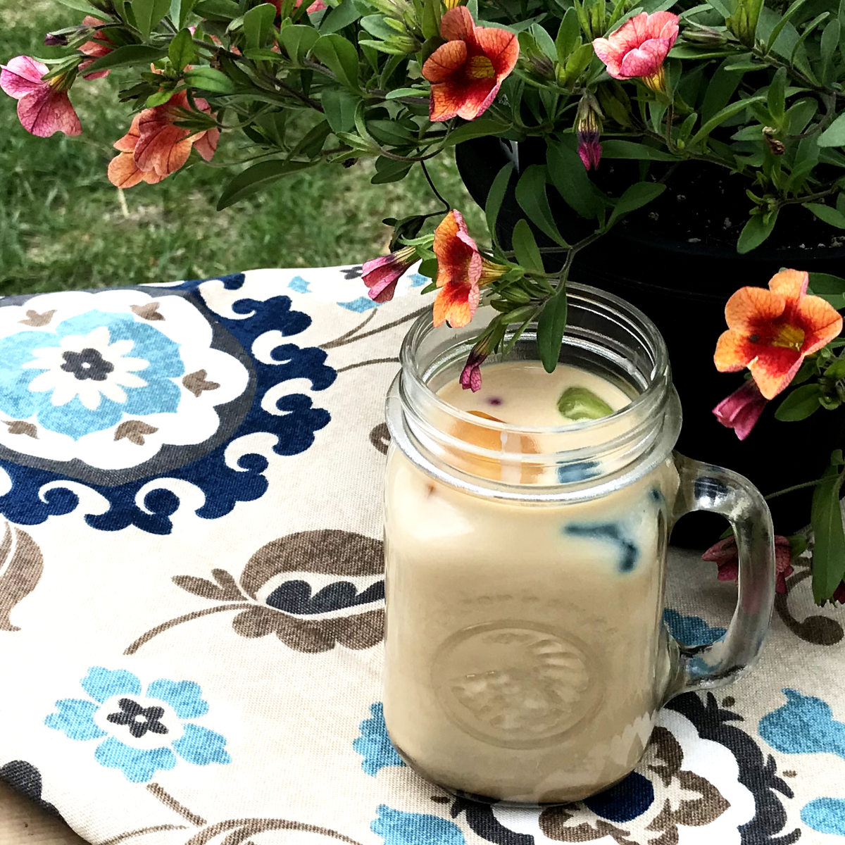 Mug of ice coffee on placemat with flowers