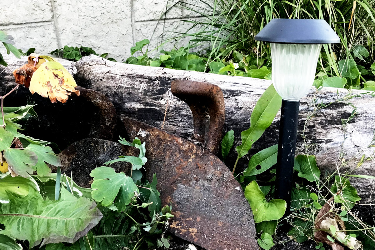 rusty plow shares and a solar lamp against a log