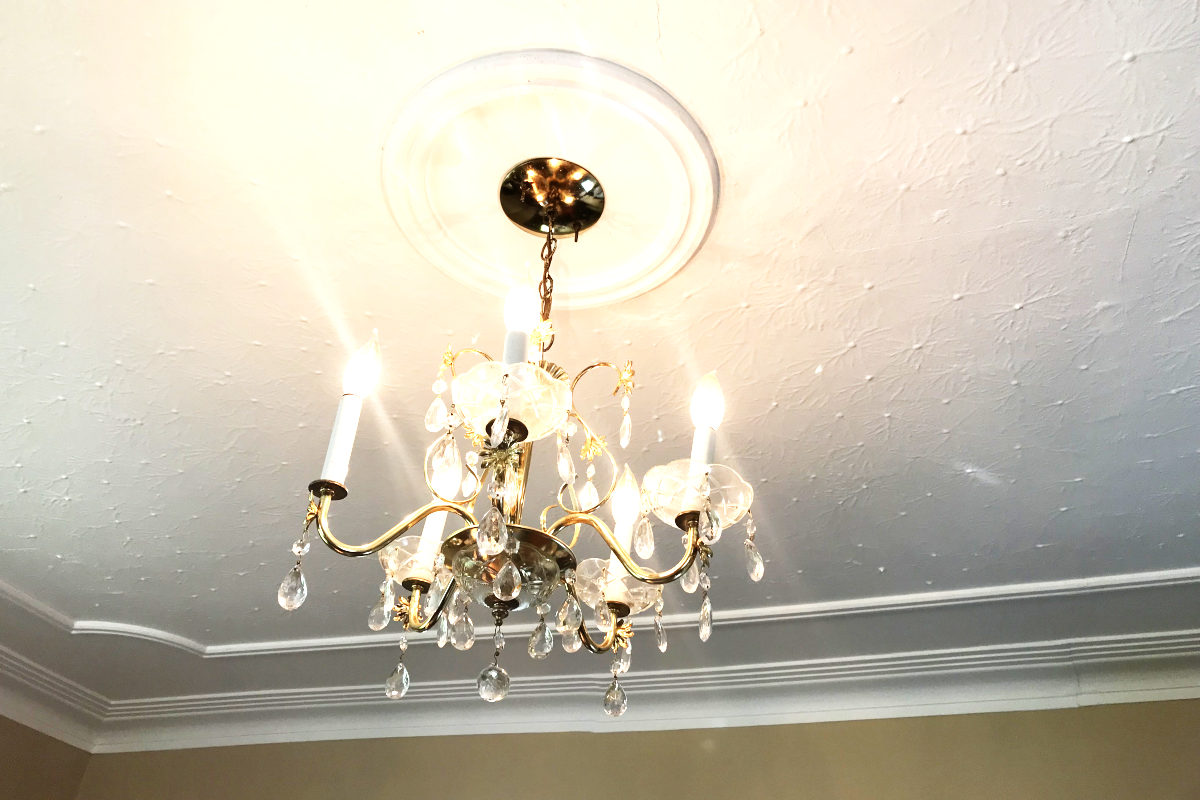 brass chandelier with five lights and glass tear drops. Ceiling has plaster crown moldings.