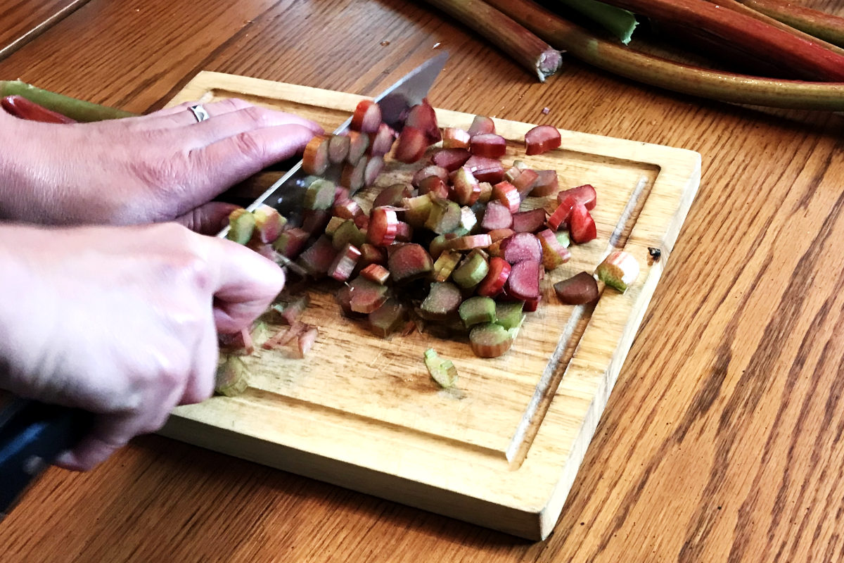 chopping rhubarb on a wooden cutting board for rhubarb dessert