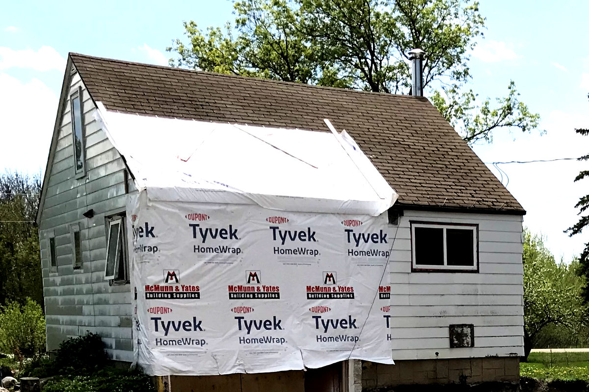 House and roof patched with house wrap after removing entryway of old house remodel.