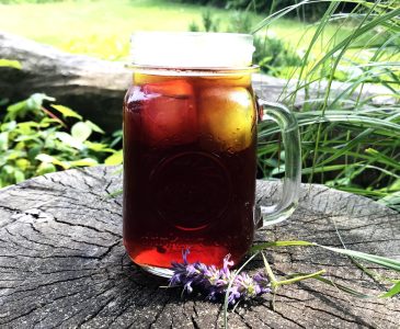 clear mug of homemade iced tea on a tree stump