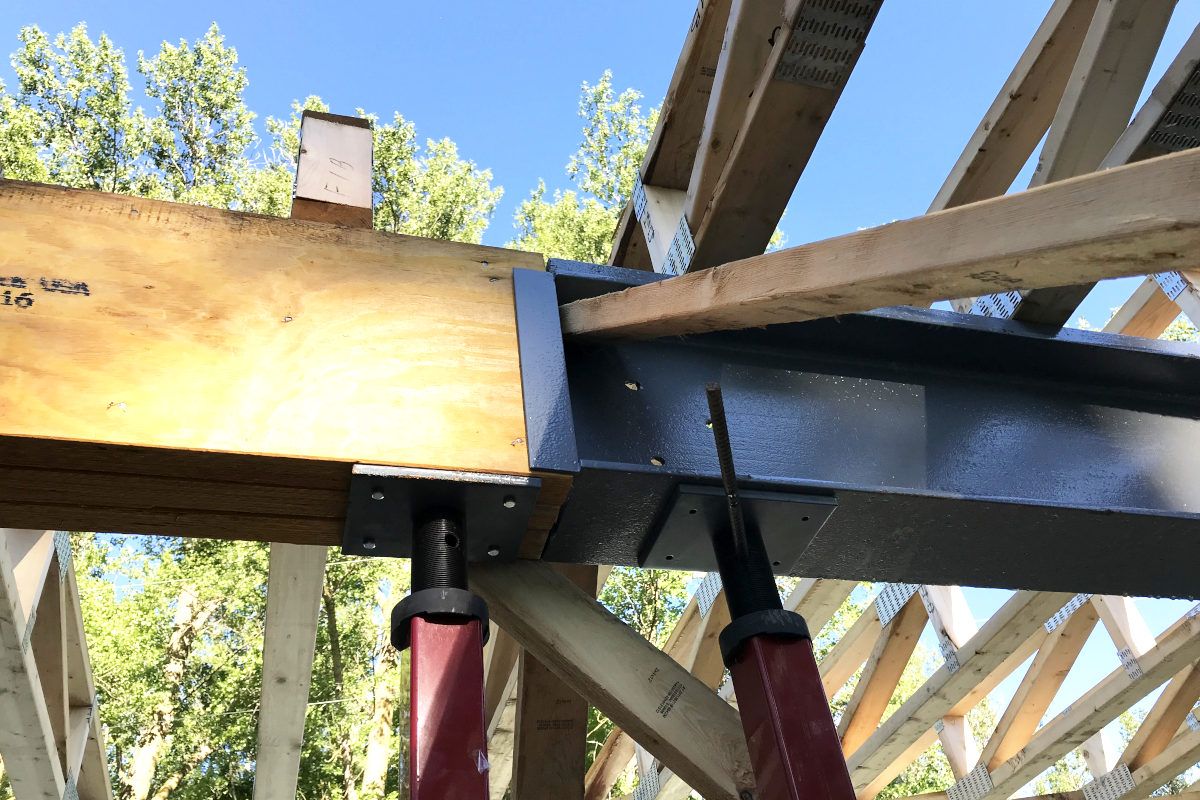 joint of the wood and steel beams with teleposts in the old house remodel, sky above