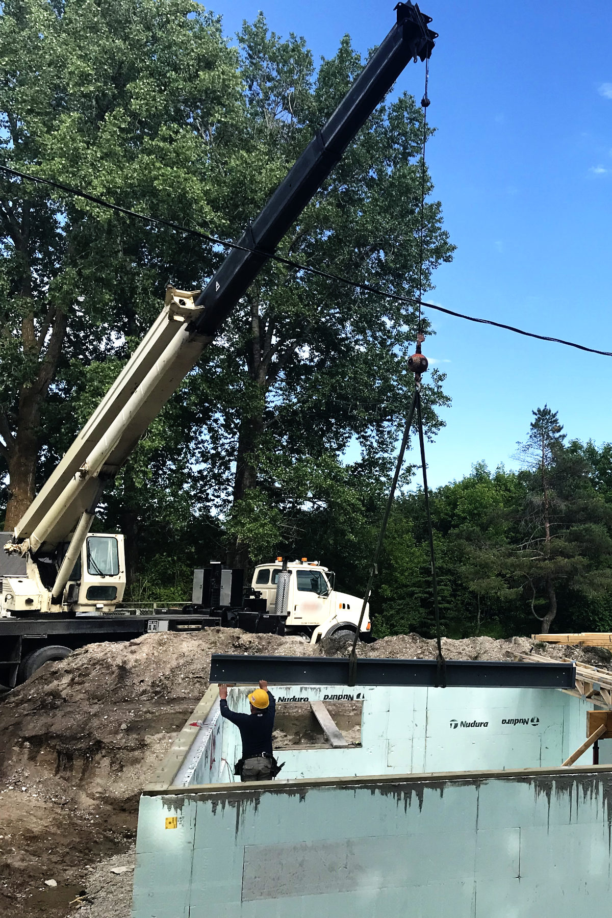 crane lifting steel beam for placement in basement addition of old house remodel