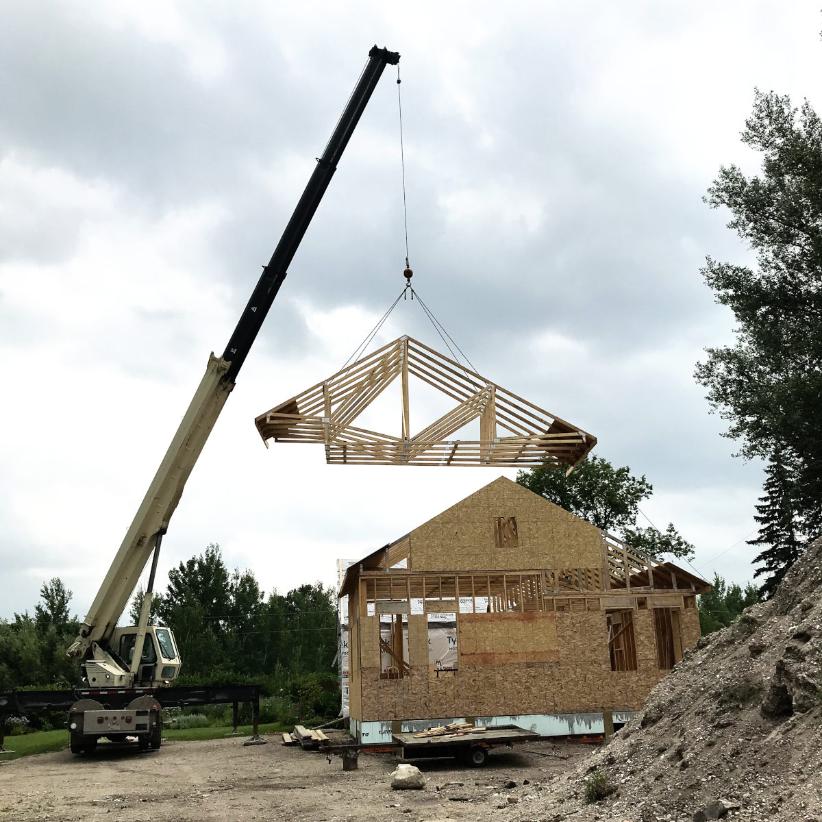 Crane raising roof trusses on the addition for the old house remodel