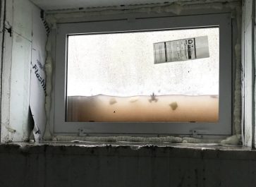 water halfway up windows in window wells of old house remodel. Frog in water.