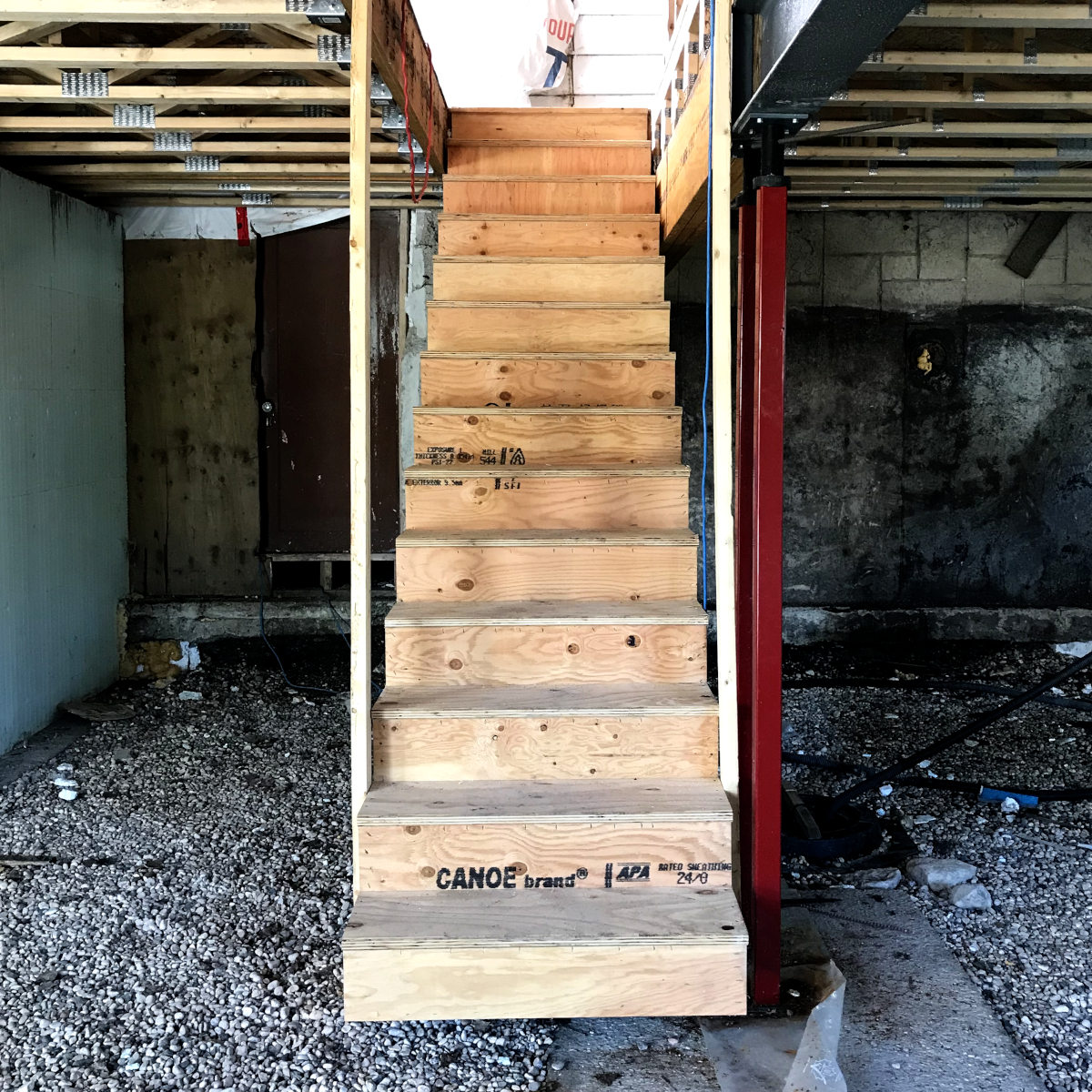 looking up at new stairs leading down to the basement of the addition of the old house remodel.