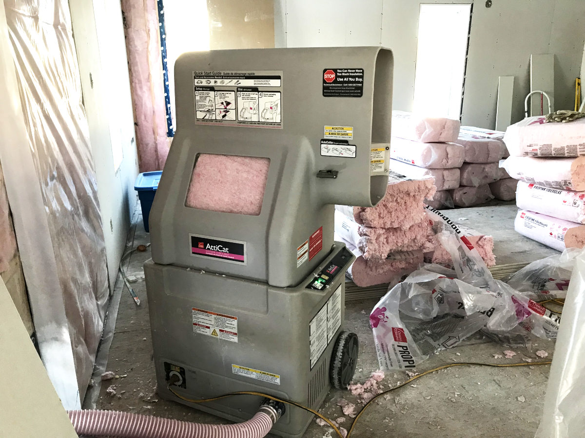 Attic insulation blower and piles of bags of insulation on floor