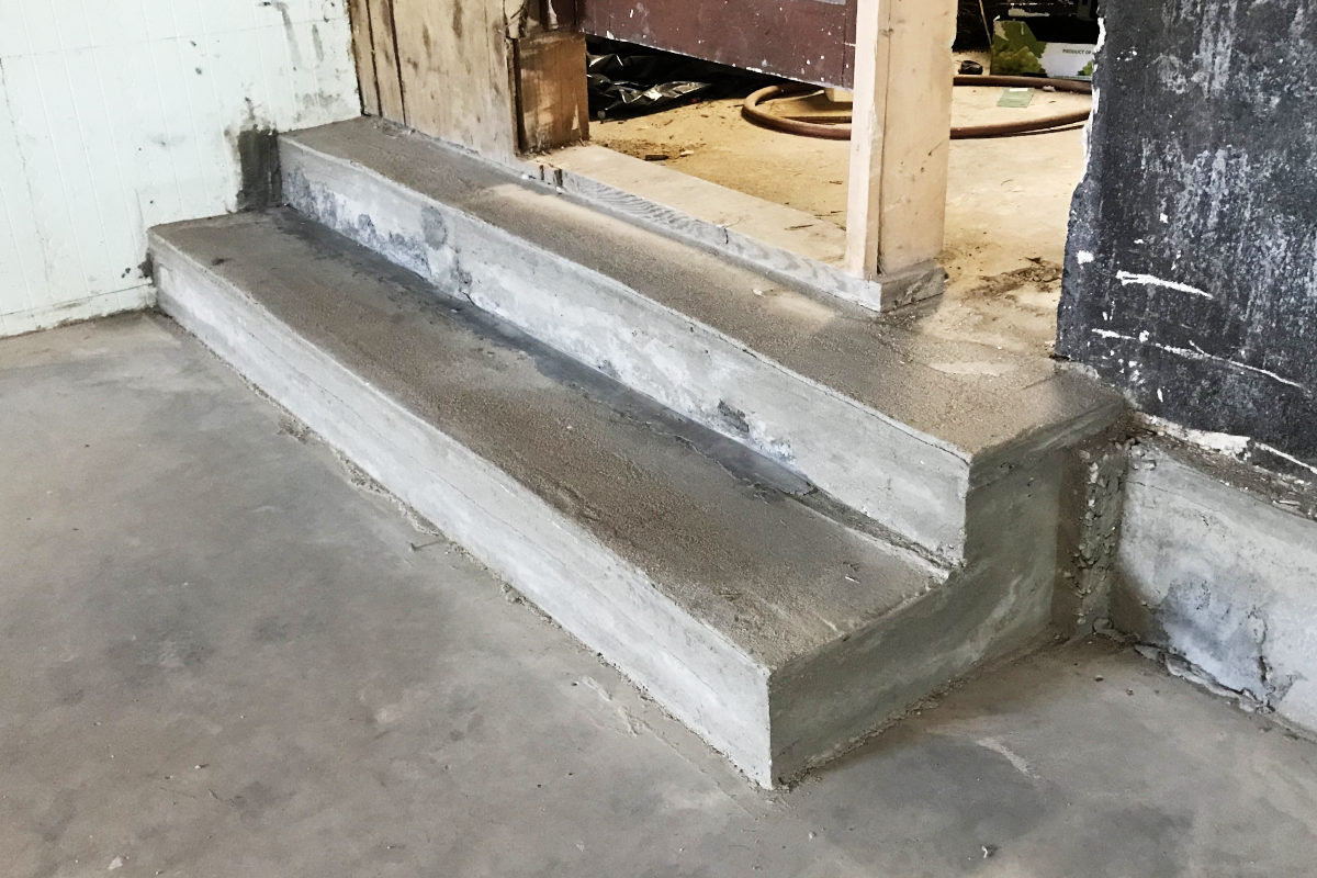 newly poured concrete step in basement of old house remodel