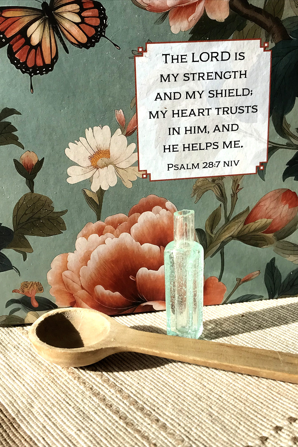 tiny bubble glass vial with teaspoon and painted flower background