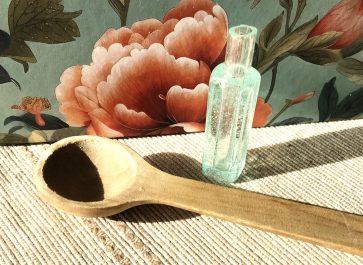 bubble glass vial and teaspoon with painted flower background