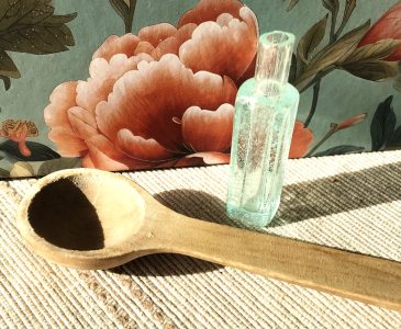 bubble glass vial and teaspoon with painted flower background