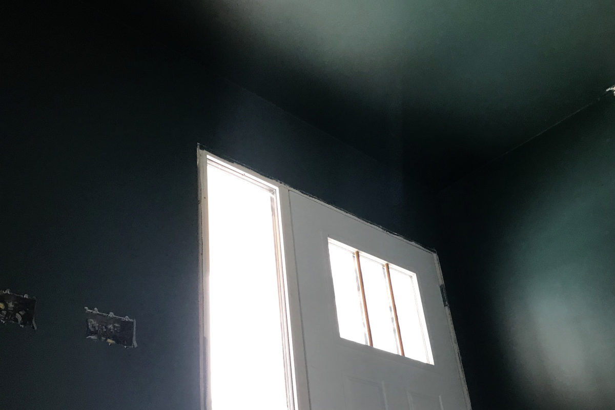 Dark green-grey teal walls and ceiling, with door.