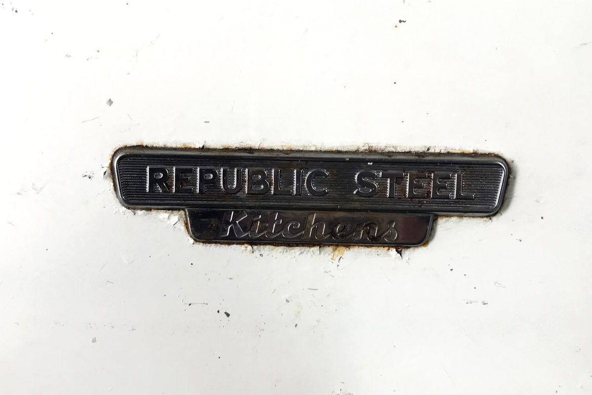 brand plate reading Republic Steel Kitchens, from the enamel sink's metal cabinet
