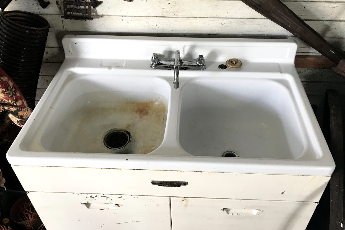 top view of old enamel sink which has rust and stains on one side.