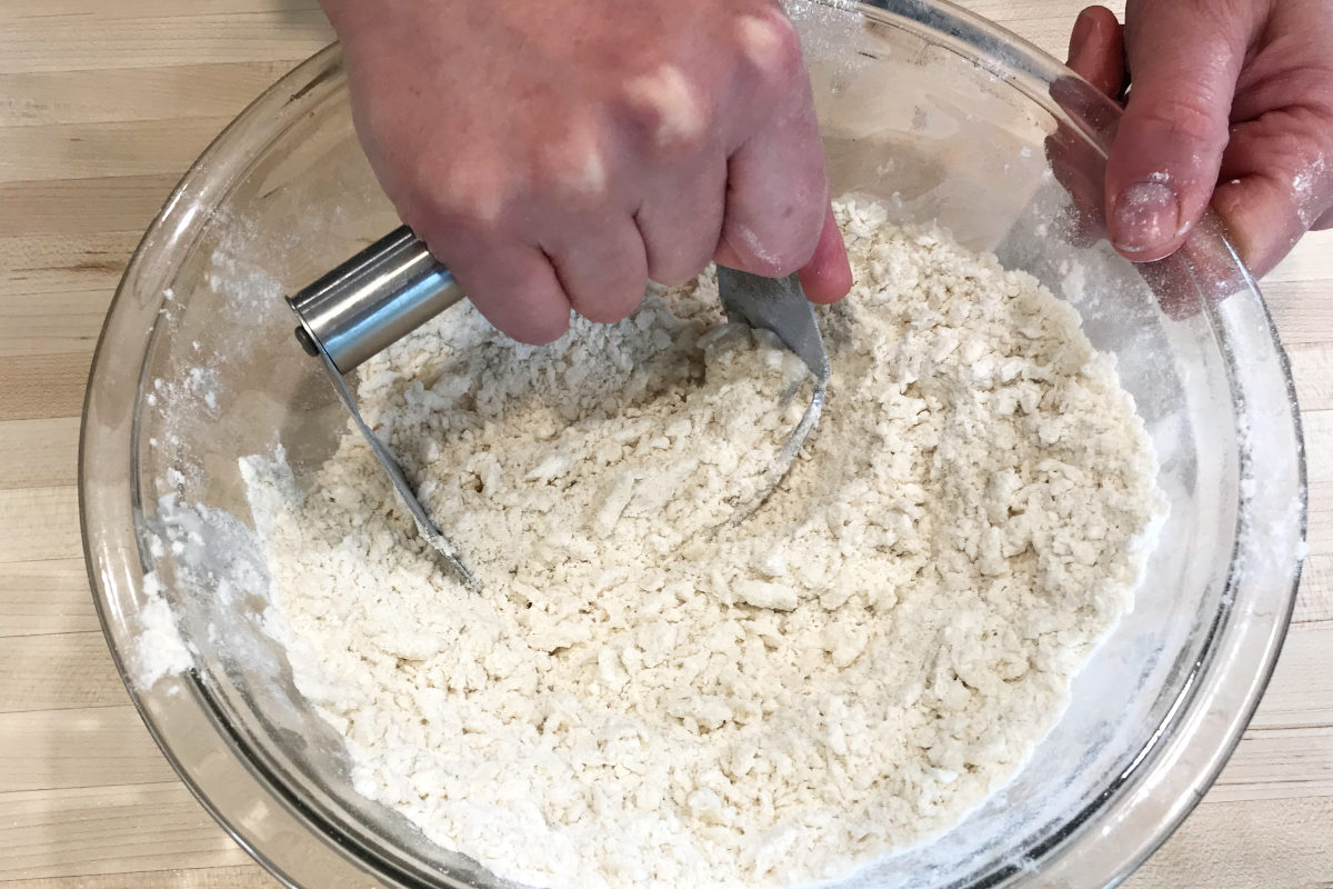 cutting together the dry ingredients and lard in a bowl with a pastry cutter for platz