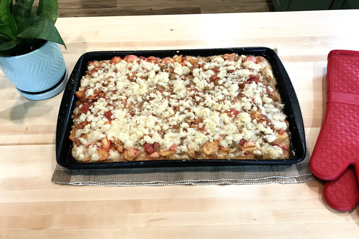 Platz in a pan, fresh from the oven, with oven mitts and a plant on butcher block counter