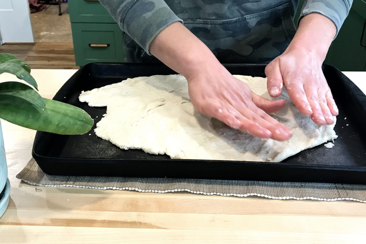 spreading dough for platz in a cookie sheet with hands