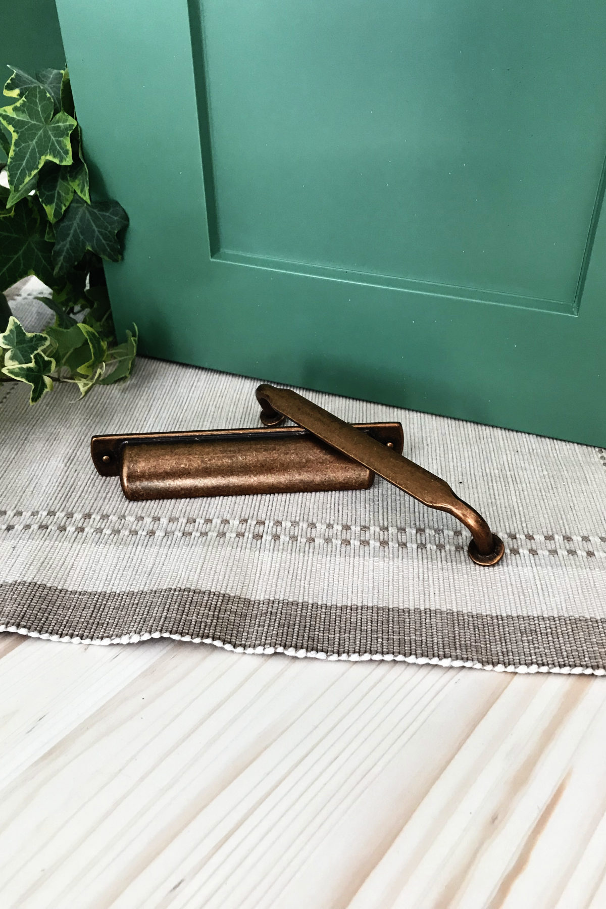 Sico's Restful Green cabinet door, old brass colored cabinet pulls, and maple butcher block counter with ivy and placemat.