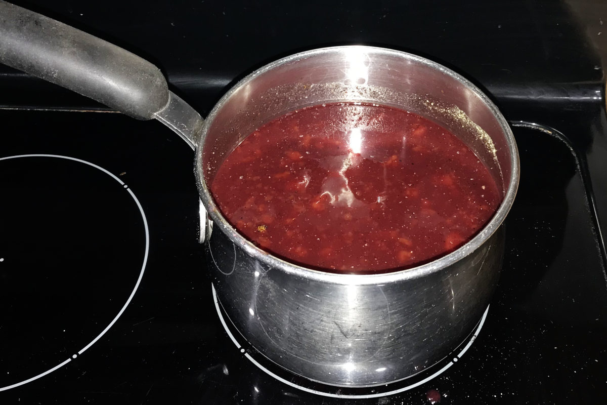chokecherry or chokeberry BBQ sauce ingredients stirred together in a pot on the stove
