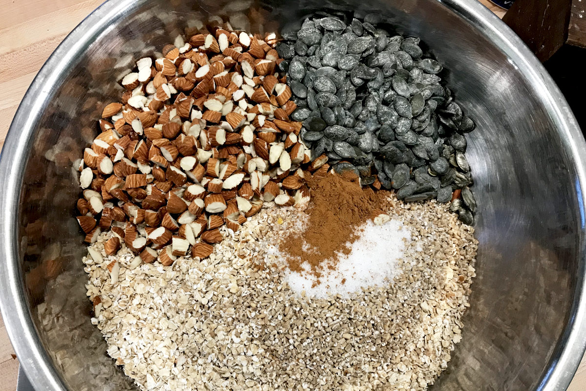 stainless steel bowl with piles of ingredients for homemade granola