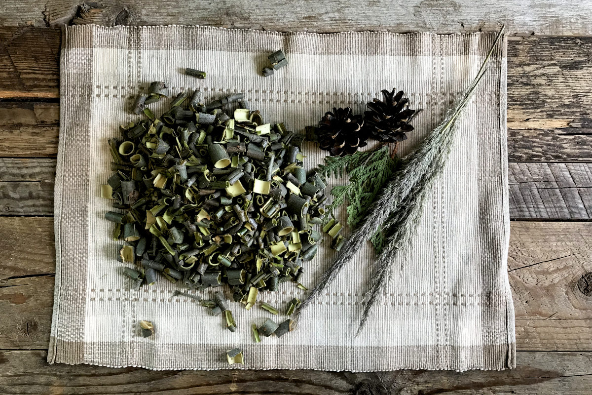 pile of peeled and cut willow bark on place mat with greenery on weathered wood