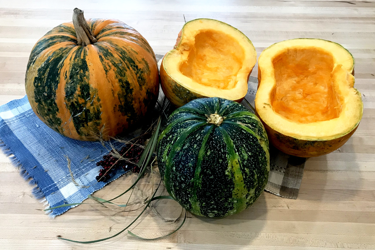 whole and halved styrian hulless pumpkins on placemats on butcher block.
