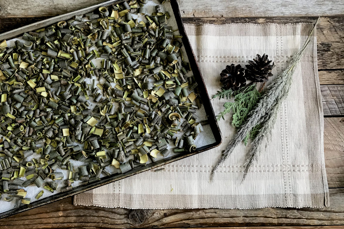 cut willow bark laid out in a pan lined with paper towel, on a place mat with greenery on weathered wood