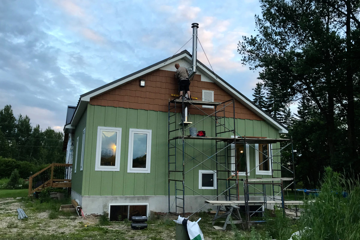 Kent installing siding at the peak of the gable, on scaffolding